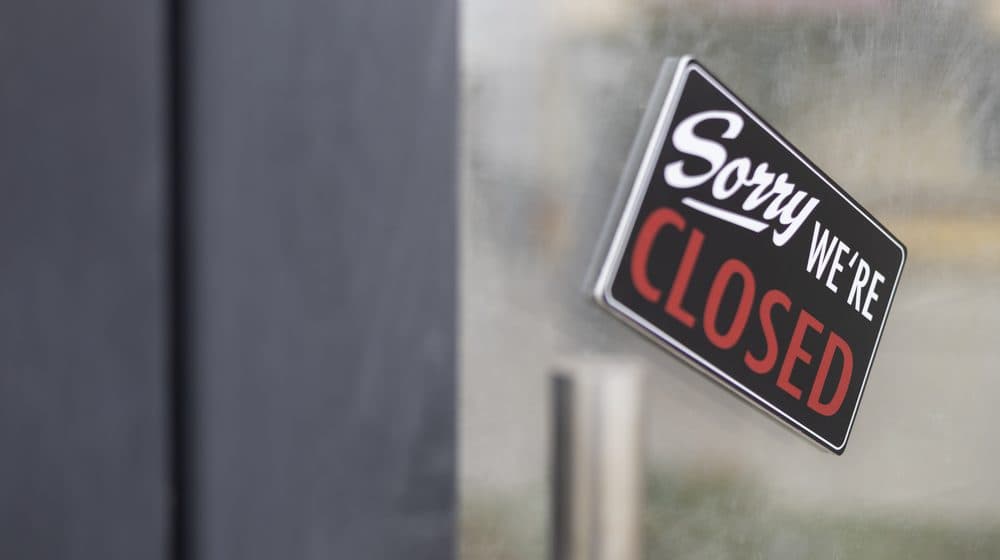 A "closed" sign hanging on a shop door.