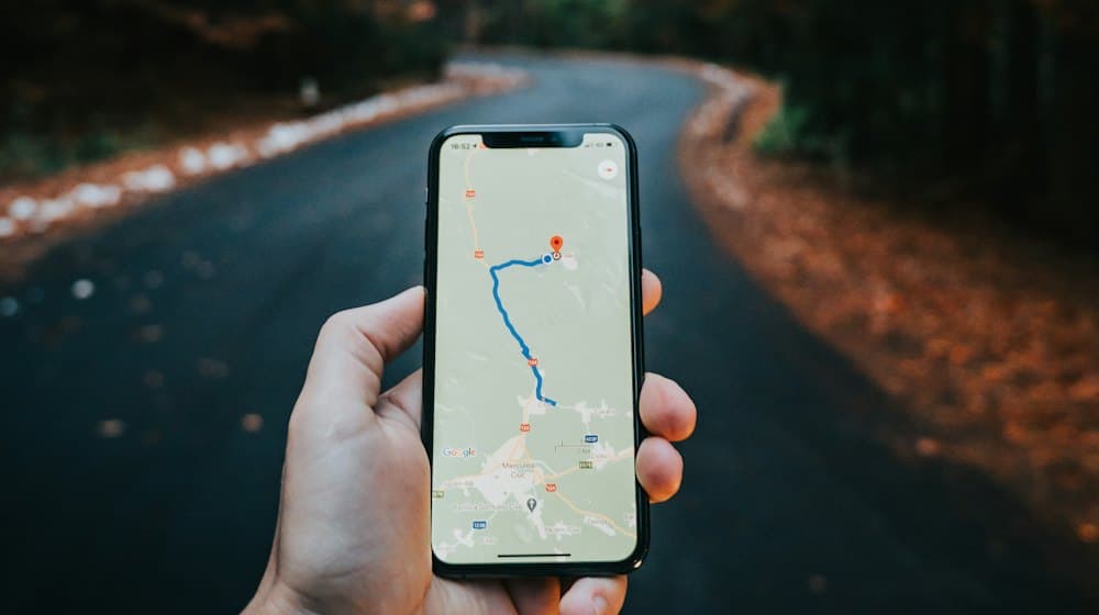 Una mano sosteniendo un móvil con una ruta de Google Maps en pantalla.