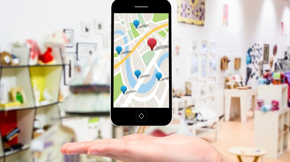 A hand holding a phone with a map open, looking for a business.