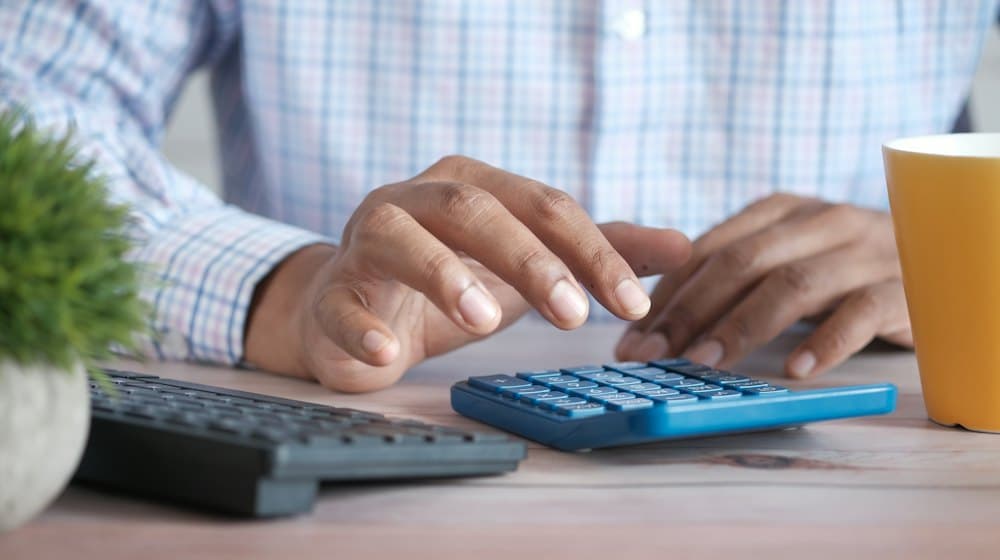 Un dueño de negocio haciendo cuentas con una calculadora.